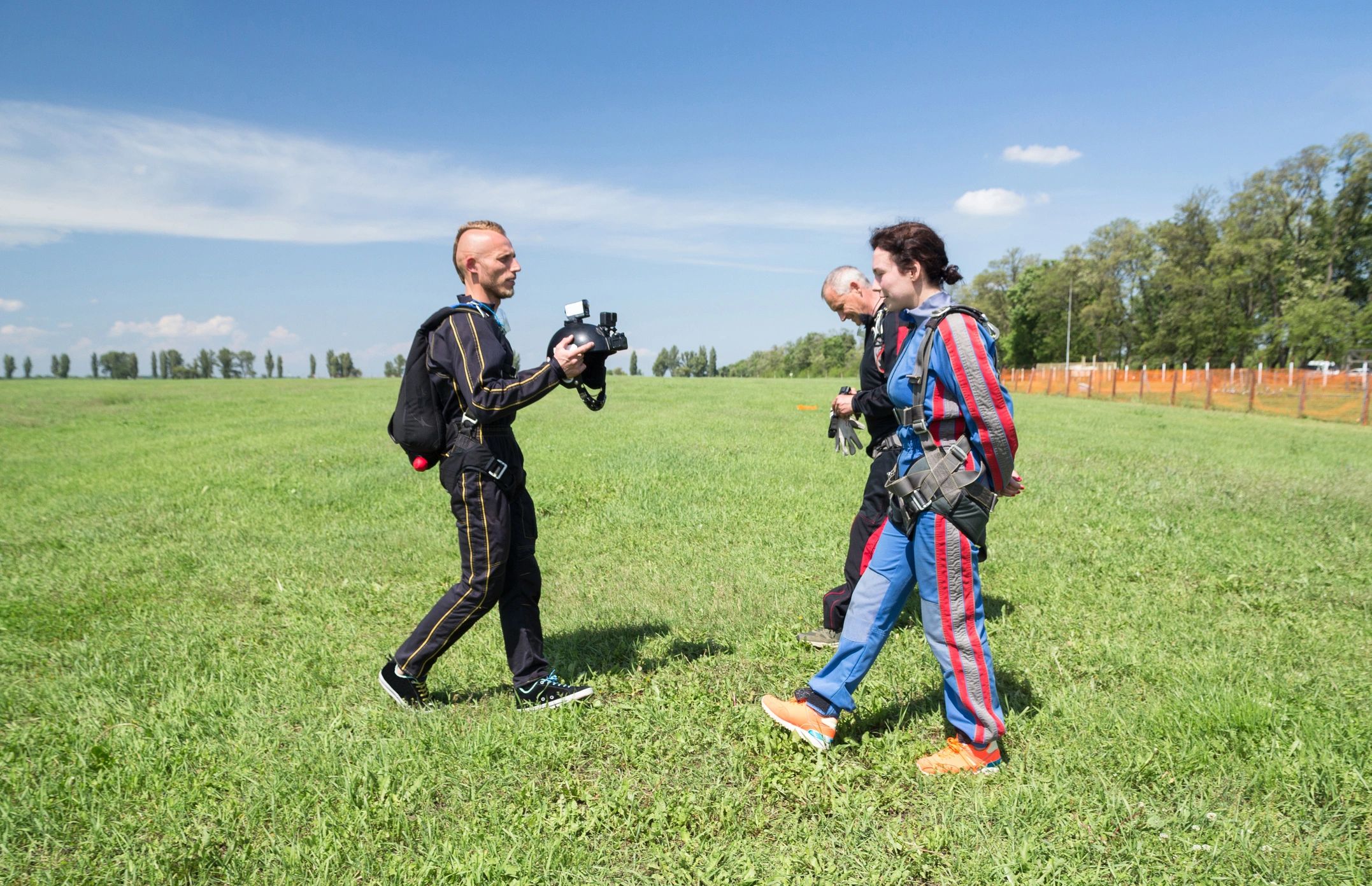 Adventure videographer and skydivers walking to a plane